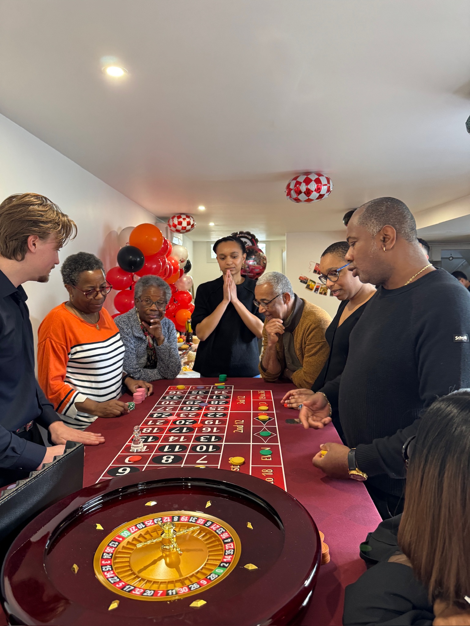 Famille réunie autour de la roulette LEYGACY pour un anniversaire, ballons en fond